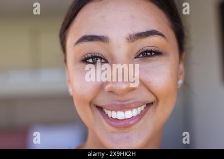 Eine zweirassige junge Frau, die zu Hause lächelt und Freude zeigt Stockfoto