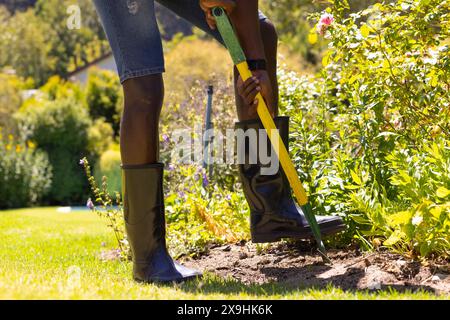 Ein junger Afroamerikaner, der Stiefel trägt und draußen gräbt Stockfoto