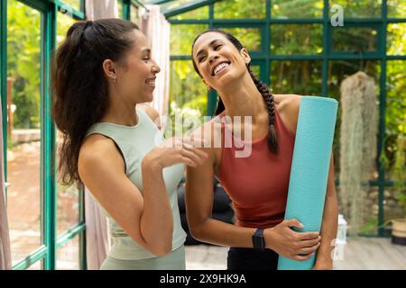 Das Glashaus-Studio beherbergt verschiedene Yoga-Schülerinnen Stockfoto