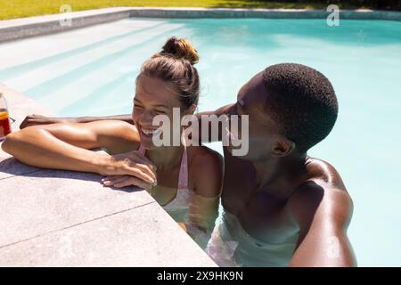 Ein vielfältiges junges Paar, das die Zeit draußen im Pool genießt Stockfoto