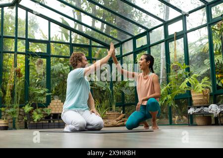 Im Glass House Studio haben verschiedene Yogastudenten High Five Stockfoto