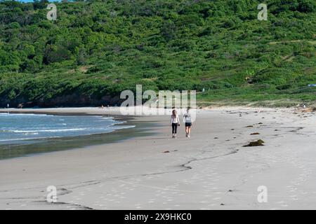 Zwei Damen von hinten gehen an einem leeren Strand entlang Stockfoto