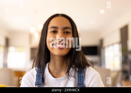 Ein birassisches junges Mädchen, das einen Jeansanzug trägt und zu Hause lächelt Stockfoto