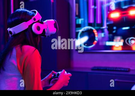 Ein birassisches junges Mädchen zu Hause, das ein rotes Hemd trägt und einen Game Controller hält Stockfoto