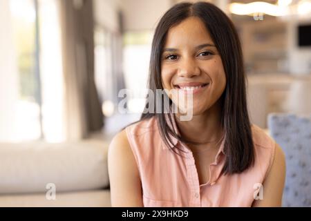 Ein birassisches Mädchen, das zu Hause lächelt und ein hellrosa Hemd trägt Stockfoto