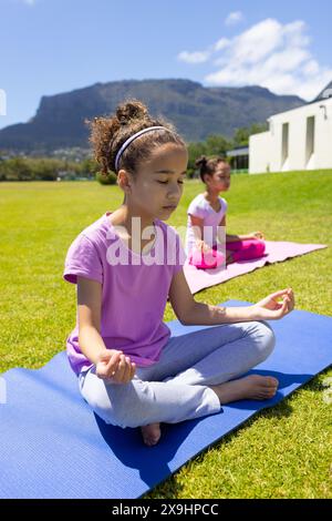 Zwei Frauen üben Yoga im Freien, eine mit geschlossenen Augen in Meditation Stockfoto