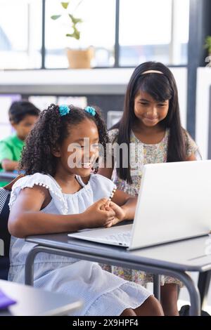 In der Schule sahen zwei junge weibliche Schülerinnen auf einen Laptop-Bildschirm im Klassenzimmer Stockfoto