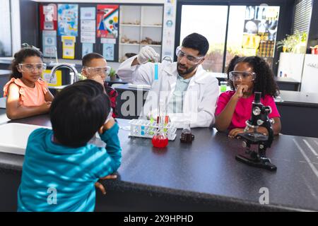 Ein junger asiatischer Lehrer führt ein Wissenschaftsexperiment für aufmerksame Kinder in der Schule durch Stockfoto