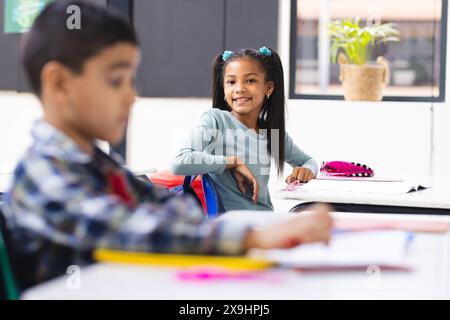 In der Schule, junge birassische Jungen und Mädchen, die sich auf ihr Studium im Klassenzimmer konzentrieren Stockfoto