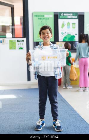 In der Schule lächelt ein birassischer Junge mit Plastikmüll im Klassenzimmer Stockfoto