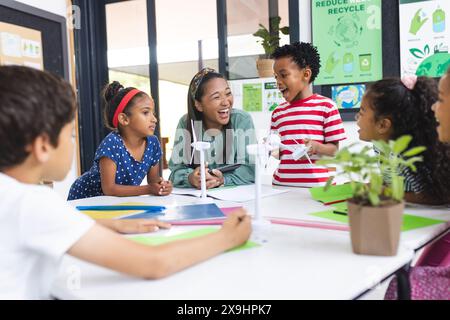 In der Schule lacht ein afroamerikanischer Lehrer mittleren Alters mit verschiedenen Schülern Stockfoto