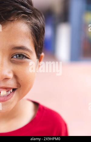 In der Schule, draußen, lächelt ein birassischer Junge mit einem roten Hemd Stockfoto