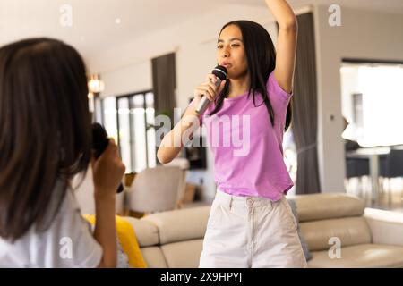 Zwei birassische junge Schwestern singen und nehmen zu Hause auf Stockfoto