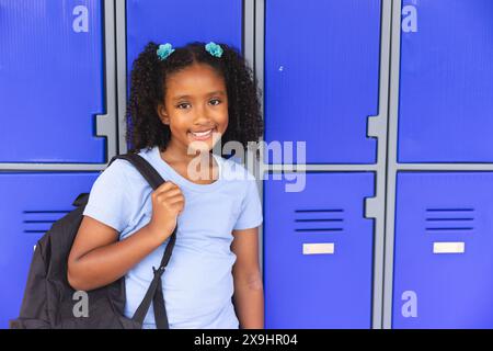 Biracial Girl steht neben den Schließfächern der Schule, mit Kopierraum Stockfoto