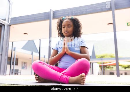 Biracial Girl praktiziert Yoga im Freien in der Schule Stockfoto