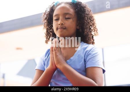 Biracial Girl praktiziert Yoga im Freien in der Schule Stockfoto