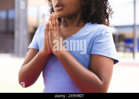 Biracial Girl praktiziert Yoga im Freien in der Schule Stockfoto