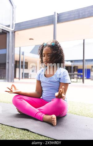 Biracial Girl praktiziert Yoga in der Schule, mit Kopierraum Stockfoto