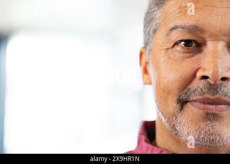 Zu Hause, zweirassiger älterer Mann mit kurzen grauen Haaren und Bart, der in die Kamera schaut, Kopierraum. Mit rotem Hemd, verschwommenem Hintergrund mit natürlichem Licht Stockfoto