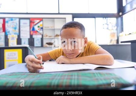 Biracial Boy konzentriert sich auf seine Schularbeit in der Schule Stockfoto