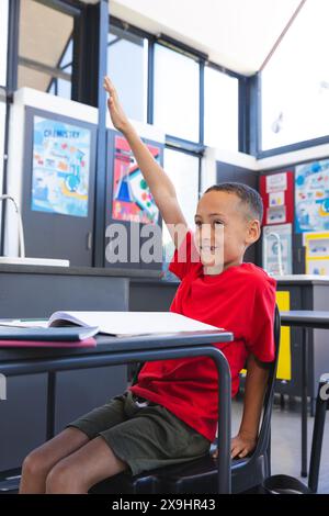 Birassischer Junge hebt Hand im Klassenzimmer in der Schule. Eifriger Schüler nimmt am Schulunterricht Teil und zeigt aktives Lernen. Stockfoto