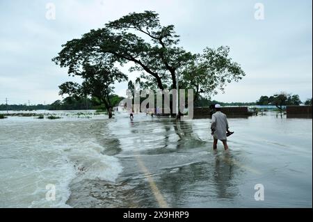Sylhet, Bangladesch. 30. Mai 2024. Die Bewohner von Sylhets Gowainghat upazila waten durch eine überflutete Hauptstraße in der Gegend von Lafnaut, die seit gestern unter Wasser getaucht ist, als der Regen von Zyklon Remals Nachwirkungen Wasser aus den umliegenden Hügeln sprudelt. Es wird festgestellt, dass viele Menschen ihre Häuser verlassen und in sichere Unterkünfte gegangen sind. Die tief liegenden und Hasengebiete von drei Gewerkschaften in Sylhets Jaintapur upazila wurden durch Sturzfluten überschwemmt, die durch starke Regenfälle und Wasser von Berghängen ausgelöst wurden. Rund 300 000 Menschen in vier upazilas sind aufgrund der plötzlichen Überschwemmungen im Wasser gefangen. Stockfoto