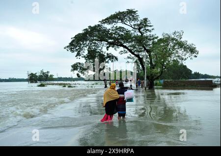 Sylhet, Bangladesch. 30. Mai 2024. Die Bewohner von Sylhets Gowainghat upazila waten durch eine überflutete Hauptstraße in der Gegend von Lafnaut, die seit gestern unter Wasser getaucht ist, als der Regen von Zyklon Remals Nachwirkungen Wasser aus den umliegenden Hügeln sprudelt. Es wird festgestellt, dass viele Menschen ihre Häuser verlassen und in sichere Unterkünfte gegangen sind. Die tief liegenden und Hasengebiete von drei Gewerkschaften in Sylhets Jaintapur upazila wurden durch Sturzfluten überschwemmt, die durch starke Regenfälle und Wasser von Berghängen ausgelöst wurden. Rund 300 000 Menschen in vier upazilas sind aufgrund der plötzlichen Überschwemmungen im Wasser gefangen. Stockfoto