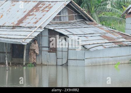 Sylhet, Bangladesch. 30. Mai 2024. Eine Frau steht in einem untergetauchten Haus in der Gegend von Sarighat an Sylhets Tamabil-Straße in Jaintapur upazila. Viele Bewohner haben sich wegen der starken Regenfälle vom Zyklon Remal in sichere Zufluchtsorte evakuiert. Die plötzlichen Überschwemmungen, die durch Wasser verursacht wurden, das aus den Bergen von Meghalaya absteigt, haben etwa drei Seenopfer in Jaintapur, Goainghat, Kanaighat und Jakiganj upazilas gefangen. Stockfoto