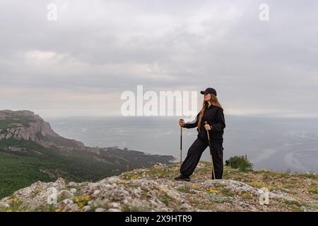 Eine Frau steht auf einem felsigen Hügel mit Blick auf das Meer Stockfoto