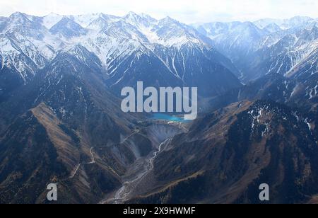 Alpiner Issyk-See in einer Bergschlucht mit schneebedeckten Gipfeln und Straßen, Blick von oben, Luftaufnahmen Stockfoto