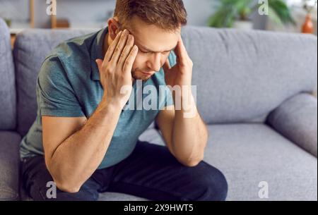 Ein Mann, Der An Kopfschmerzen Auf Dem Sofa Zu Hause Leidet Stockfoto
