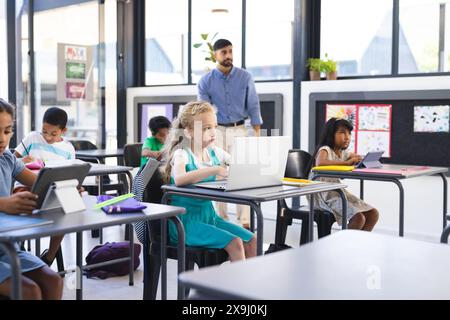 In der Schule, im Klassenzimmer, konzentriert sich eine Gruppe junger Schüler auf ihre Laptops Stockfoto