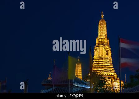 Ein Bild vom zentralen Prang des Tempels Wat Arun, nachts, hinter winkenden Fahnen. Stockfoto