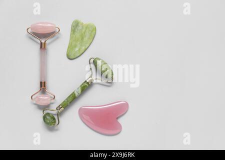 Jadewalzen und Gua Sha auf grauem Hintergrund Stockfoto