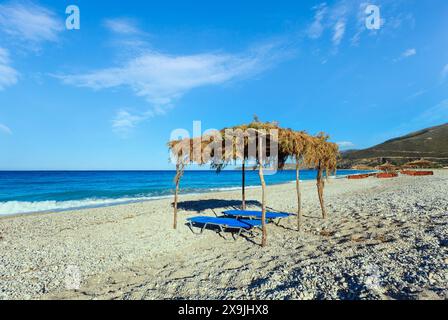 Sommer morgen kiesiger Strand mit Sonnenliegen und Baldachin (Borsh, Albanien). Stockfoto