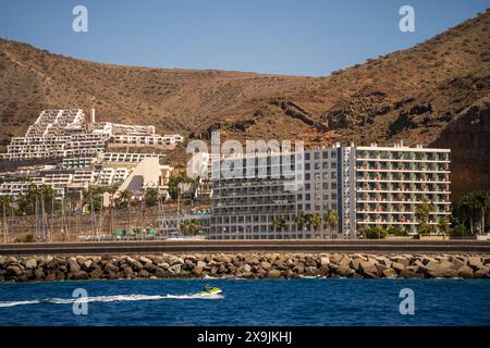 Puerto Rico, Gran Canaria, Spanien : Blick auf Schiff und Jetski auf die Kurstadt Puerto Rico, südlich Gran Canaria, Spanien mit großen Hotelgebäuden Stockfoto