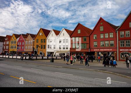 BERGEN, NORWEGEN - 11. AUGUST 2016: Touristen gehen und sitzen vor den berühmten Holzhäusern in Bergen, Norwegen Stockfoto