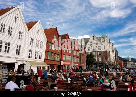 BERGEN, NORWEGEN - 11. AUGUST 2016: Touristen gehen und sitzen vor den berühmten Holzhäusern in Bergen, Norwegen Stockfoto