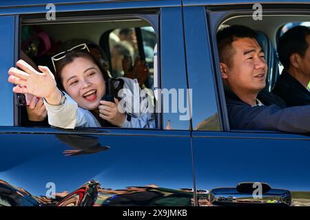 (240601) -- USU, 1. Juni 2024 (Xinhua) -- Ein Tourist winkt den Einheimischen an einer Tankstelle entlang des Duku Highway in Usu City, nordwestchinesischer Autonomen Region Xinjiang Uygur, 1. Juni 2024. Der Duku Highway, einer der schönsten Straßen Chinas, nahm seinen Betrieb am Samstag nach einer jährlichen Wintersperrung wieder auf, die normalerweise im Oktober beginnt. In diesem Jahr nahm der Verkehr auf der 560 km langen Autobahn früher wieder auf als in den letzten fünf Jahren. Die Autobahn verbindet Dushanzi im Norden der Autonomen Region Xinjiang Uygur mit der Stadt Kuqa im Süden und verläuft durch verschiedene Landschaften, darunter g Stockfoto