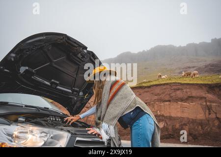 Eine Frau mit gelbem Hut steht neben einem Auto mit aufgesetzter Kapuze, Touristen in den peruanischen anden Stockfoto