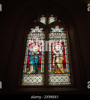 Buntes Buntglasfenster mit religiösen Figuren in einem gotischen Bogenrahmen in der St. Mary's Church Purton Wiltshire Stockfoto