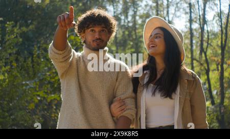 Sorglos verheiratetes multiethnisches Paar hispanische Frau Mädchen afroamerikanischer Mann Junge Walking Point Finger halten Hände. Weibliche Frau, männlicher Ehemann, lächeln Stockfoto