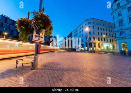 Brünner Stadtbild in der Abenddämmerung mit Lichtspuren, Bewegungsunschärfe, Bank an der Straßenbahnhaltestelle am Freiheitsplatz, Namesti Svobody, dem Hauptplatz in der Altstadt von Brünn. Stockfoto