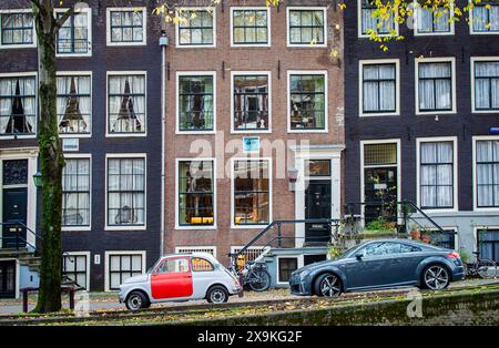 Amsterdam, Niederlande, 20. November 2022. Blick auf traditionelle Gebäude in Amsterdam im Herbst mit Autos, Fahrrädern und Bäumen. Stockfoto