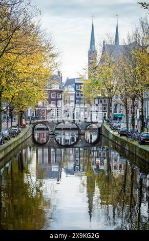 Amsterdam, Niederlande, 20. November 2022. Ruhiger Morgen von Amsterdam im Herbst mit Brücke, Gebäuden, Fahrrädern, Bäumen und Reflexionen im Kanal. Stockfoto