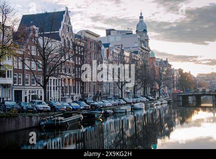 Amsterdam, Niederlande, 20. November 2022. Blick auf den friedlichen Morgen (Sonnenaufgang) in Amsterdam, mit Häusern, Autos, Booten und Reflexionen im Kanal. Stockfoto