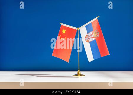 Nationalflaggen von China und Serbien auf dem Tisch vor blauem Hintergrund. Stockfoto