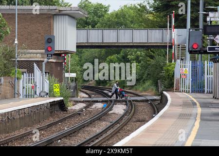 Bahnüberquerung Rainham Kent mit einer Dame und einem Kinderwagen über die Gleise Stockfoto