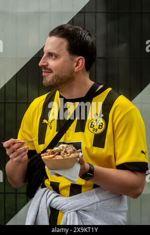 London, Großbritannien. 1. Juni 2024. Ein Dortmunder Fan isst eine Portion Chips vor dem Champions-League-Finale zwischen Real Madrid und Borussia Dortmund im Wembley-Stadion. Zusätzliche Polizei- und Sicherheitsmaßnahmen, sowie keine Alkoholverbotsschilder (in mehreren Sprachen) um das Stadion herum sind vorhanden, um die Menschenmenge zu schützen. Quelle: Stephen Chung / Alamy Live News Stockfoto