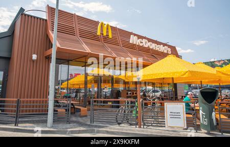 Lisniki, Kiew, Ukraine - 18. Mai 2024: Im McDonald's Fast-Food-Restaurant essen die Besucher unter freiem Himmel unter Sonnenschirmen. Es ist ein amerikanischer Mult Stockfoto